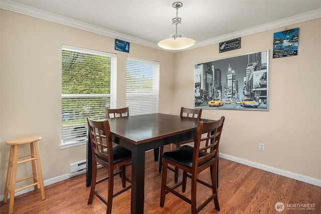 dining space with ornamental molding, wood finished floors, baseboards, and a baseboard heating unit