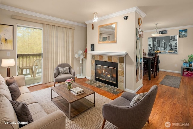 living area featuring ornamental molding, wood finished floors, a tile fireplace, and baseboards