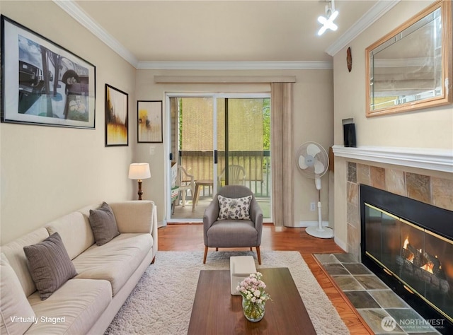 living room featuring wood finished floors, crown molding, a fireplace, and baseboards