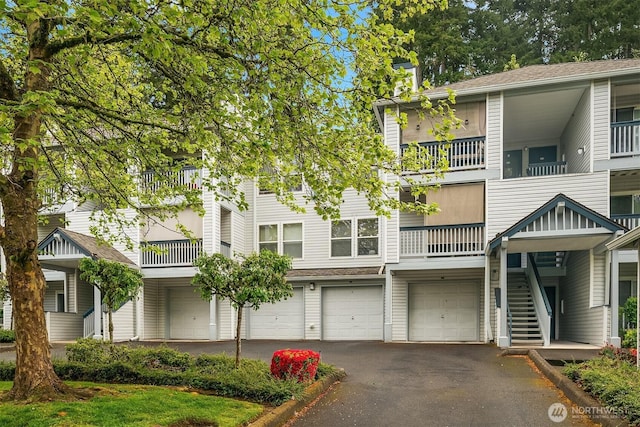 townhome / multi-family property featuring asphalt driveway, a garage, and stairs