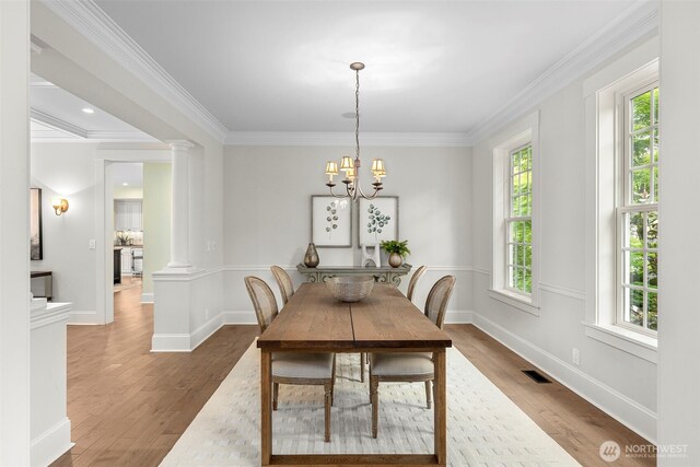 11281 Fieldstone Ln NE, Bainbridge Island, WA 98110 - dining room with crown molding, wood finished floors, ornate columns, a chandelier, and baseboards