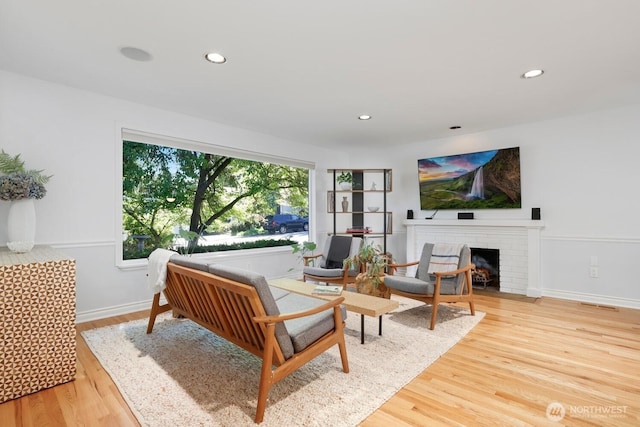 living area featuring wood finished floors, a fireplace, recessed lighting, and baseboards