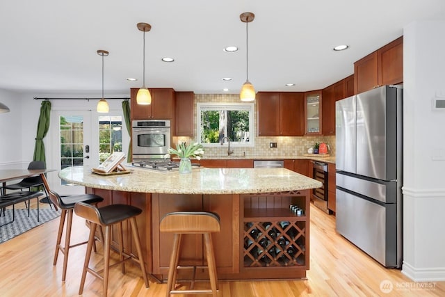 kitchen featuring stainless steel appliances, a sink, light wood-style floors, tasteful backsplash, and recessed lighting