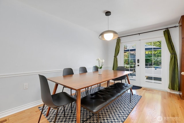 dining room with french doors, light wood finished floors, and baseboards