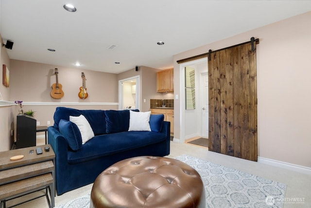 living area with a barn door, baseboards, recessed lighting, and light colored carpet