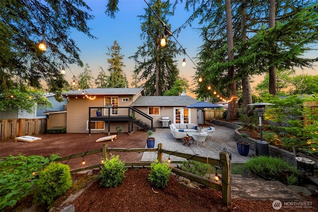 rear view of house with an outdoor living space, a deck, a patio area, french doors, and stairway