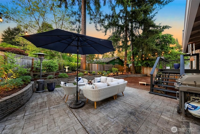 patio terrace at dusk with a fenced backyard, outdoor lounge area, a grill, and stairs