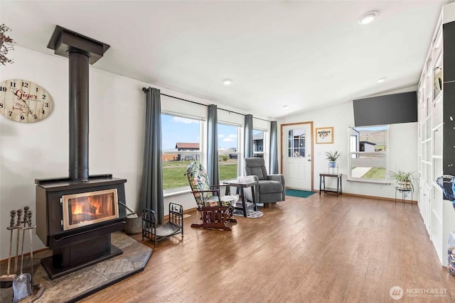 living area featuring a wood stove, wood finished floors, and a wealth of natural light