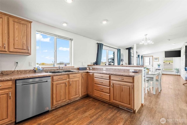 kitchen featuring stainless steel dishwasher, dark wood-style floors, plenty of natural light, a sink, and a notable chandelier