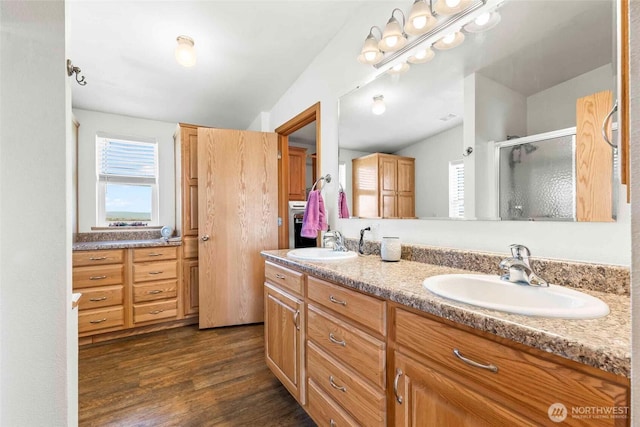 bathroom with a sink, a stall shower, double vanity, and wood finished floors