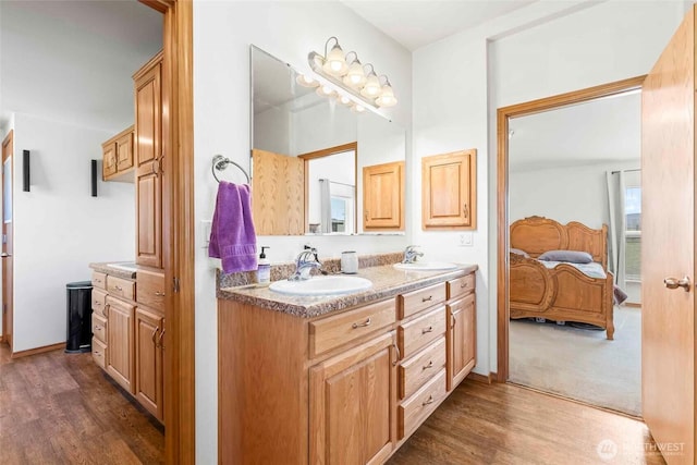 full bath featuring double vanity, a sink, connected bathroom, and wood finished floors