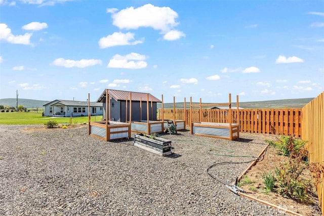 view of jungle gym with an outdoor structure, a fenced backyard, and a vegetable garden