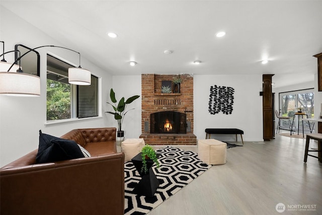 living area with plenty of natural light, a brick fireplace, recessed lighting, and wood finished floors