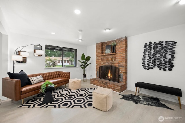 living room with a brick fireplace, recessed lighting, and wood finished floors