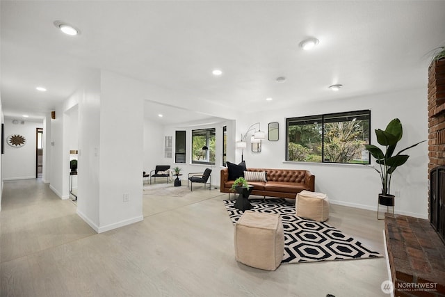 living area featuring recessed lighting, a healthy amount of sunlight, light wood-style flooring, and a fireplace