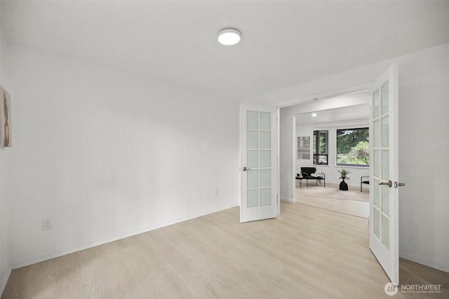 empty room with baseboards, french doors, and light wood-type flooring