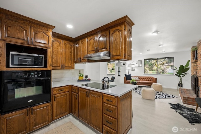 kitchen featuring light countertops, brown cabinetry, open floor plan, under cabinet range hood, and black appliances