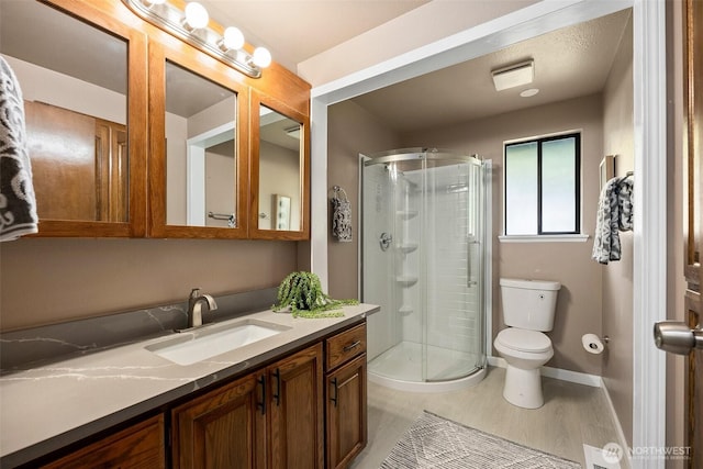 bathroom featuring vanity, baseboards, toilet, and a shower stall