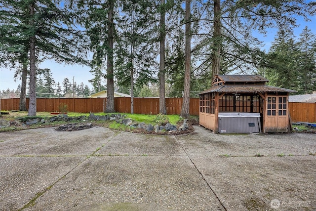 view of patio with a gazebo, a fenced backyard, and a hot tub