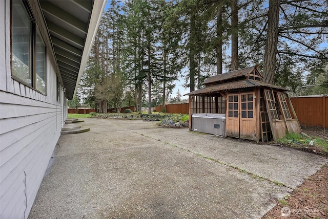 view of patio with a gazebo, a hot tub, and fence