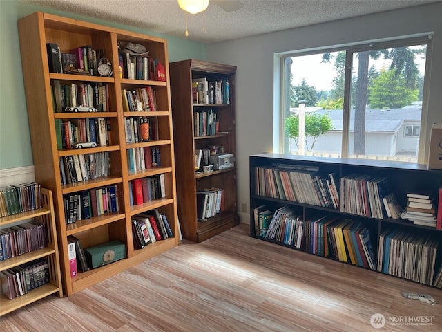 240 Parkwood Blvd, Sequim, WA 98382 - sitting room featuring bookshelves, wood finished floors, a textured ceiling, and a ceiling fan