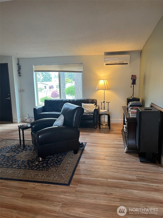 240 Parkwood Blvd, Sequim, WA 98382 - living area featuring an AC wall unit, a textured ceiling, light wood-style floors, and baseboards