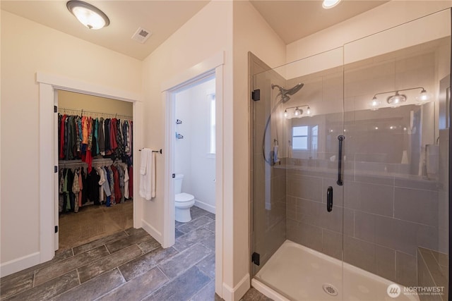 1602 Latitude Cir, Anacortes, WA 98221 - bathroom featuring a shower stall, toilet, a walk in closet, baseboards, and stone finish flooring