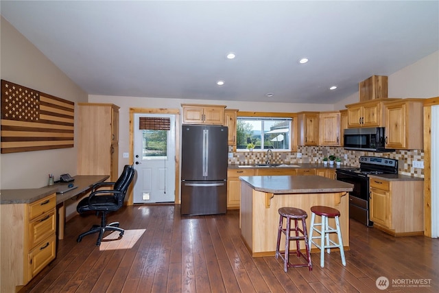 kitchen with a sink, appliances with stainless steel finishes, vaulted ceiling, and a kitchen bar