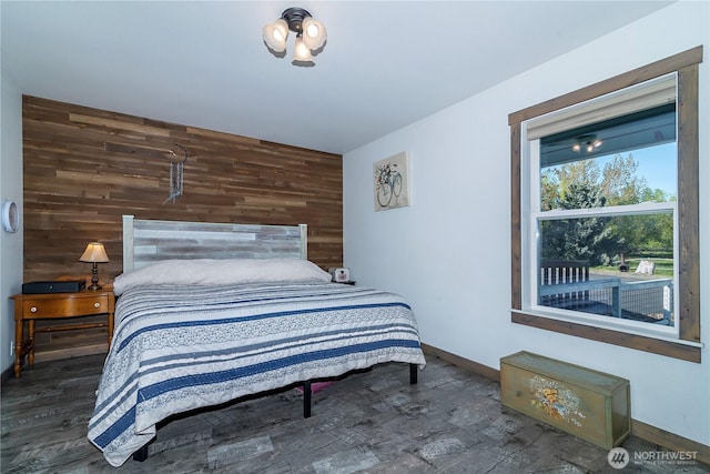 bedroom featuring wooden walls, baseboards, and wood finished floors
