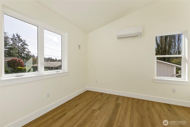 9253 6th Ave NW, Seattle, WA 98117 - empty room with baseboards, vaulted ceiling, a wall mounted air conditioner, and wood finished floors
