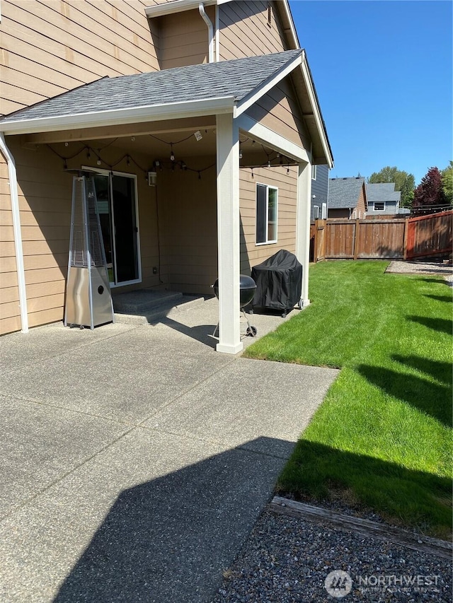 back of property with a patio, a shingled roof, fence, and a yard