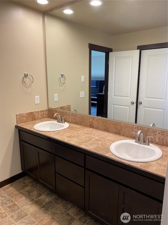 full bath with double vanity, a sink, and baseboards