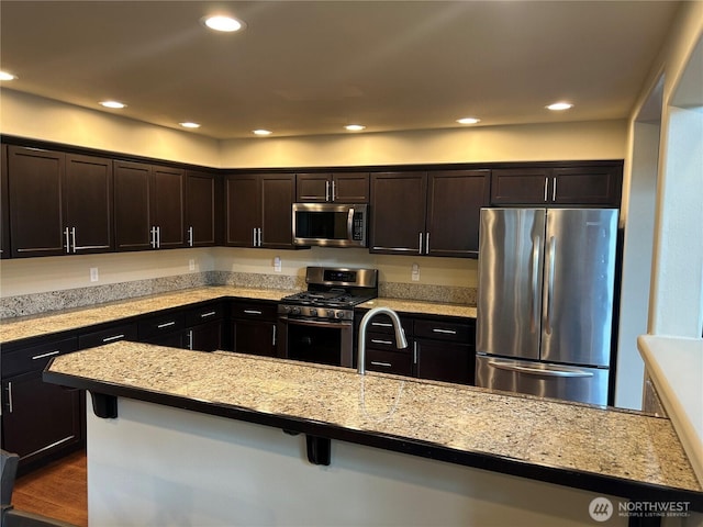 kitchen with dark brown cabinets, recessed lighting, light countertops, a sink, and stainless steel appliances