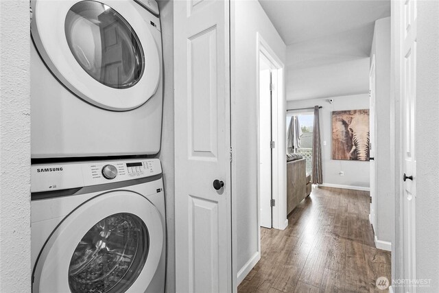 laundry room with stacked washing maching and dryer, baseboards, laundry area, and wood finished floors