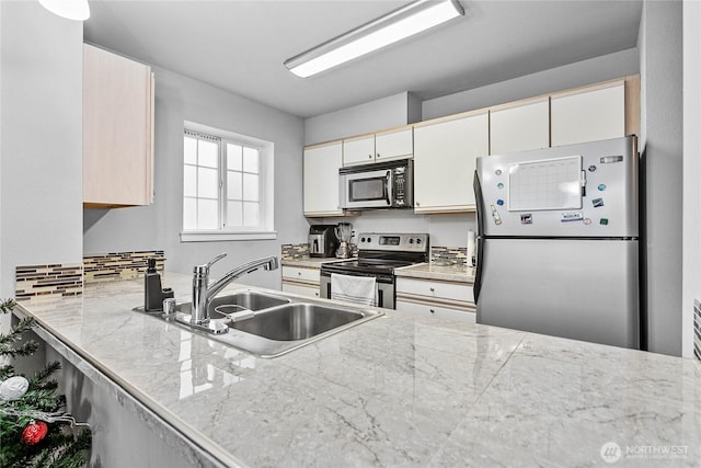kitchen with a sink, appliances with stainless steel finishes, a peninsula, and light countertops