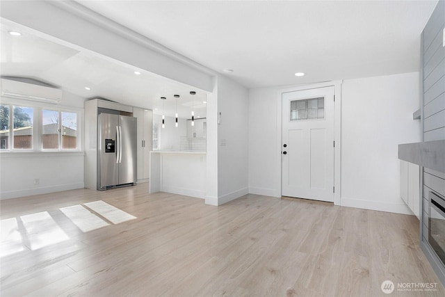 unfurnished living room with a wall mounted air conditioner, light wood-style flooring, recessed lighting, baseboards, and lofted ceiling