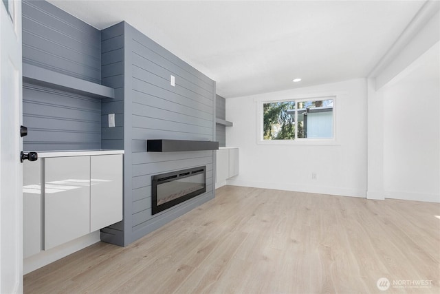 unfurnished living room featuring light wood-style floors, a large fireplace, baseboards, and recessed lighting