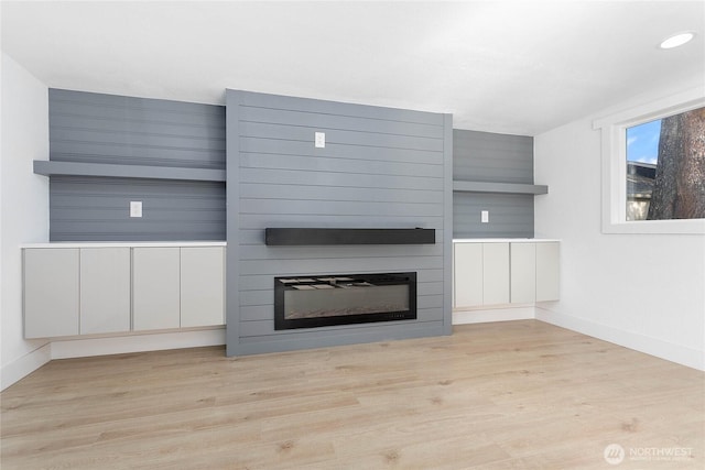unfurnished living room featuring baseboards, recessed lighting, light wood finished floors, and a large fireplace