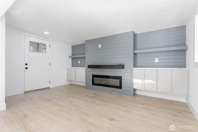 unfurnished living room with a fireplace, recessed lighting, baseboards, and light wood-style floors