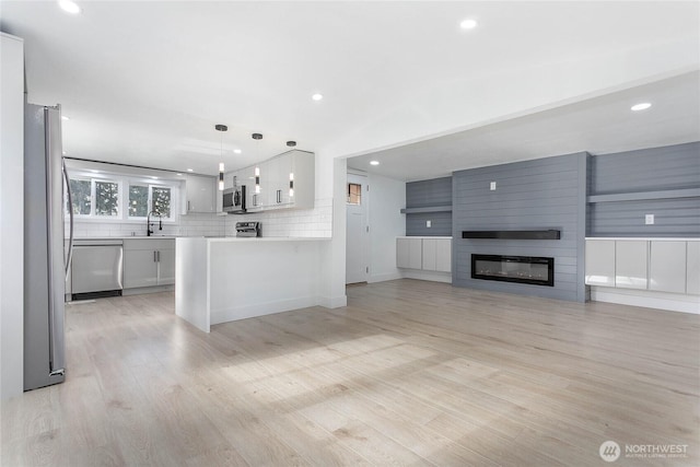 kitchen with light countertops, open floor plan, appliances with stainless steel finishes, and light wood finished floors