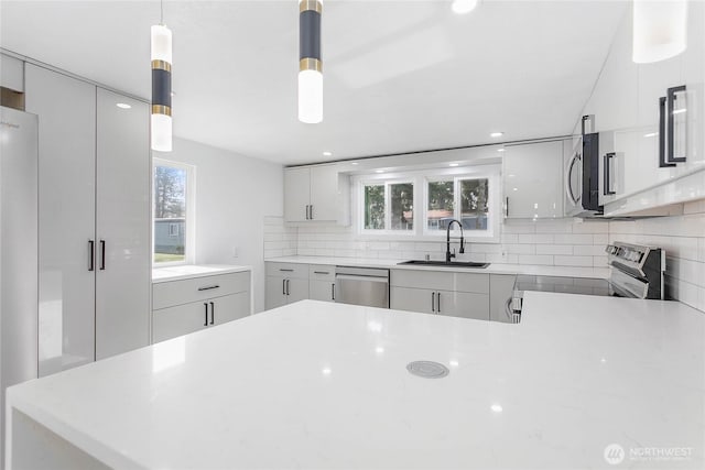 kitchen featuring a sink, modern cabinets, backsplash, and stainless steel appliances