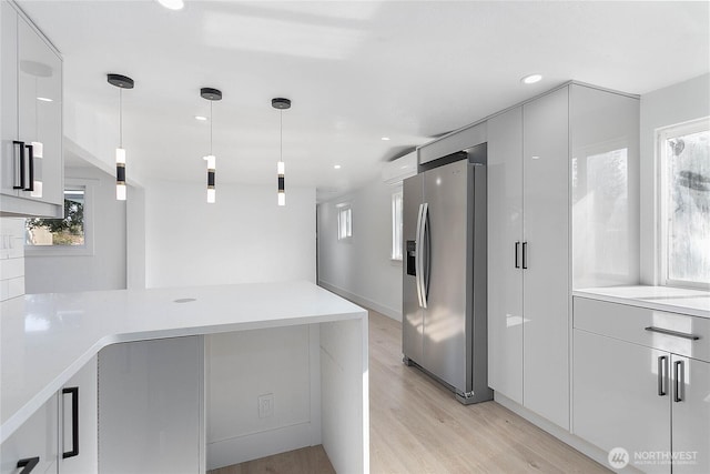 kitchen featuring light wood-style flooring, modern cabinets, stainless steel fridge with ice dispenser, and light countertops
