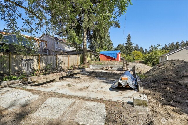 view of yard with fence, an outdoor structure, and a storage unit