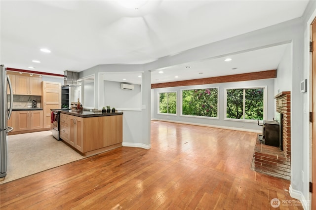 24005 SE 132nd Way, Issaquah, WA 98027 - kitchen with wall chimney exhaust hood, open floor plan, dark countertops, a fireplace, and light wood-type flooring