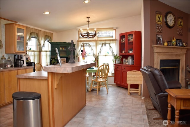 kitchen with a glass covered fireplace, glass insert cabinets, a breakfast bar area, light countertops, and a notable chandelier