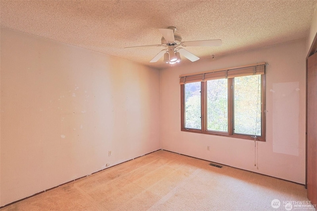 unfurnished room with light carpet, a ceiling fan, a textured ceiling, and visible vents