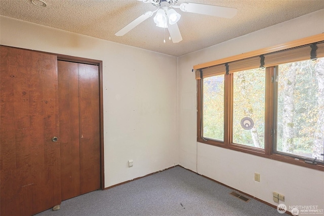 unfurnished bedroom featuring carpet floors, visible vents, multiple windows, and a closet