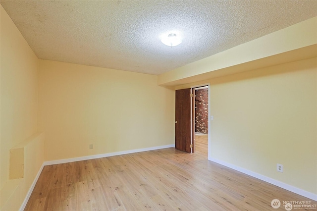 unfurnished room featuring light wood-style floors, baseboards, and a textured ceiling