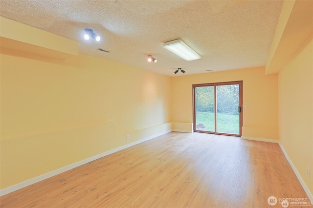 unfurnished room featuring visible vents, a textured ceiling, light wood-style flooring, and baseboards