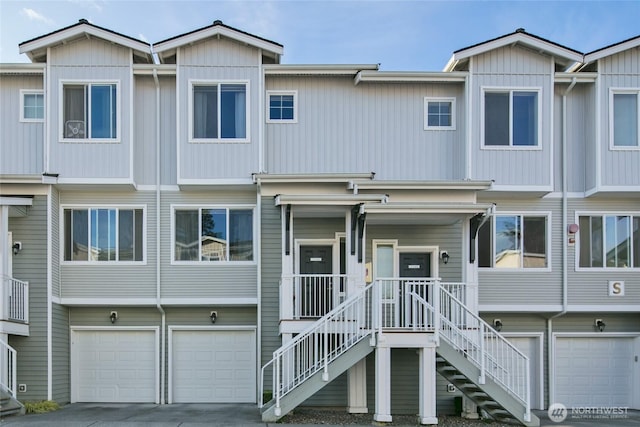 view of property featuring a garage, driveway, and stairway